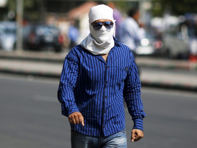 Homem caminha com o rosto coberto para se proteger do sol durante dia quente em Nova Déli. Segundo o departamento de meteorologia da Índia, a temperatura na cidade pode chegar aos 43 graus nos próximos dias - 08/06/2015