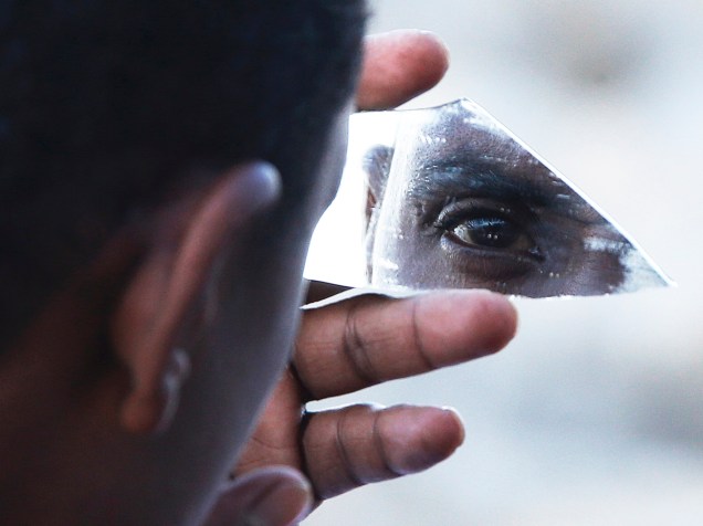 Migrante usa um pedaço de vidro como espelho durante passagem na fronteira de Saint Ludovic, entre Ventimiglia, na Itália, e Menton, na França - 17/06/2015