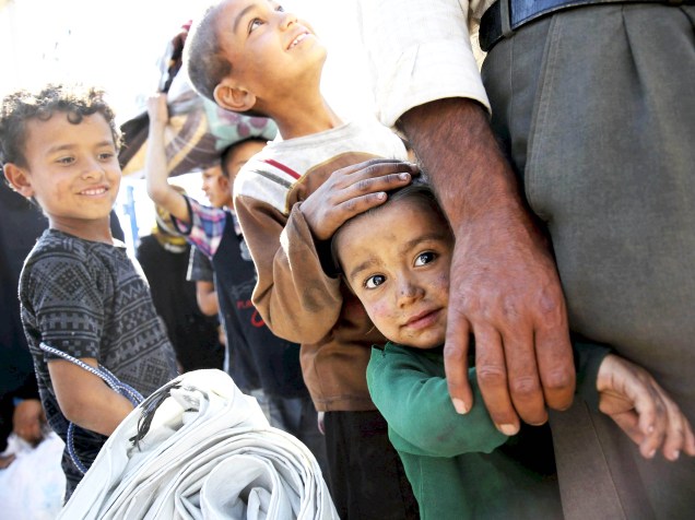 Crianças refugiadas aguardam para atravessar até a cidade de Tel Abyad, durante retorno para suas casas no portão de fronteira Akçakale, na província de Sanliurfa, na Turquia - 17/06/2015