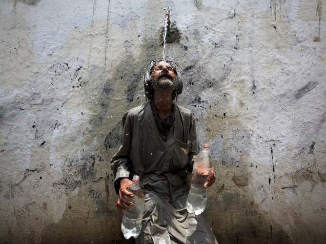 Homem se refresca em bica dágua em Karachi, no Paquistão. Onda de calor na cidade atinge os 45ºC - 23/06/2015