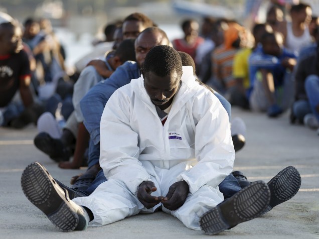 Imigrantes descansam após desembarcar em porto na região da Sicília, Itália. Barcos patrulhando o mediterrâneo encontraram mais de 2.700 imigrantes que navegavam em navios inseguros e sobrecarregados - 23/06/2015