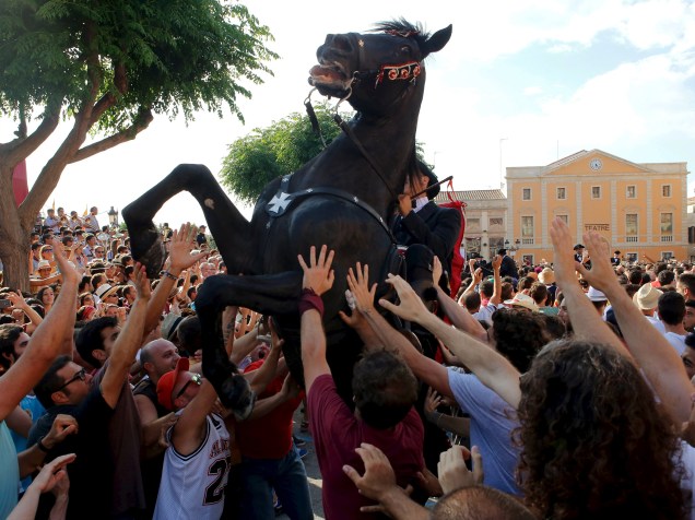 Homem montado em cavalo é cercado por multidão durante a tradicional "Fiesta of San Joan", em Ciutadella, Espanha - 23/06/2015