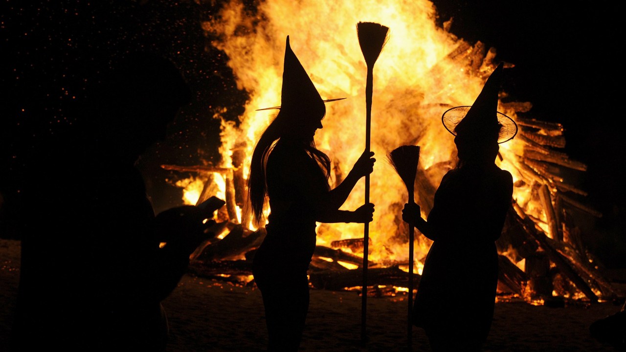 Mulheres vestidas de bruxas são fotografadas em frente a uma fogueira durante a noite de São João na praia de Gijon, norte da Espanha - 24/06/2015
