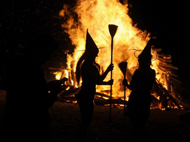 Mulheres vestidas de bruxas são fotografadas em frente a uma fogueira durante a noite de São João na praia de Gijon, norte da Espanha