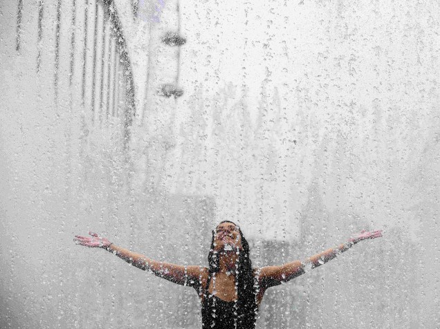 Mulher é fotografada enquanto se refresca em uma fonte durante um dia quente de verão em Londres