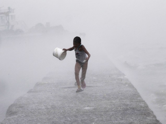 Durante forte chuva na baía de Manila, nas Filipinas, garoto correu enquanto era atingido por ondas trazidas pelo tufão Linfa, localmente conhecido como Egay