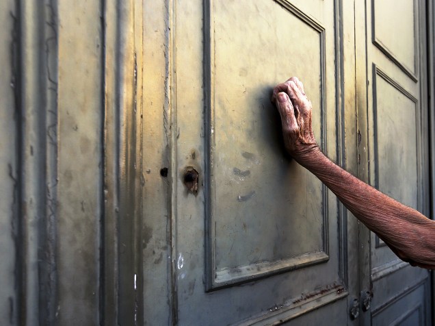 Em Atenas, pensionista se apoia na porta principal de uma agência do Banco Nacional da Grécia na espera de receber sua pensão do governo - 07/07/2015