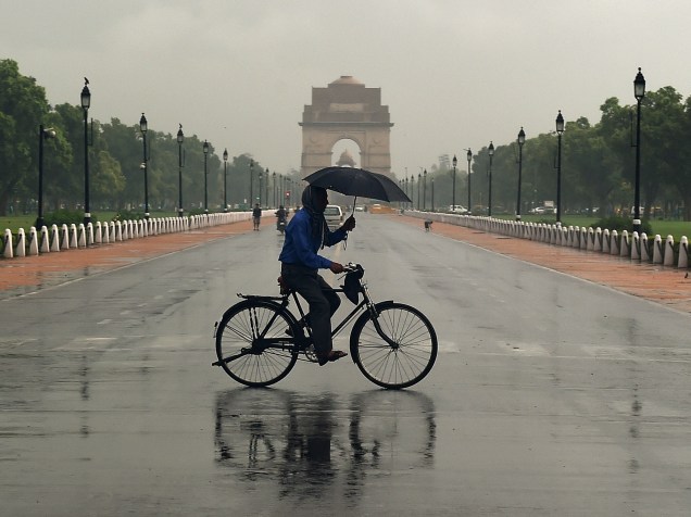 Ciclista usa um guarda-chuva enquanto atravessa o Rajpath em Nova Délhi, na Índia - 09/07/2015