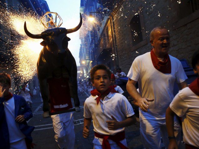 Homem carregando uma estrutura metálica em forma de um touro carregada com fogos de artifício, corre atrás dos foliões durante o festival de São Firmino, em Pamplona, norte da Espanha - 10/07/2015