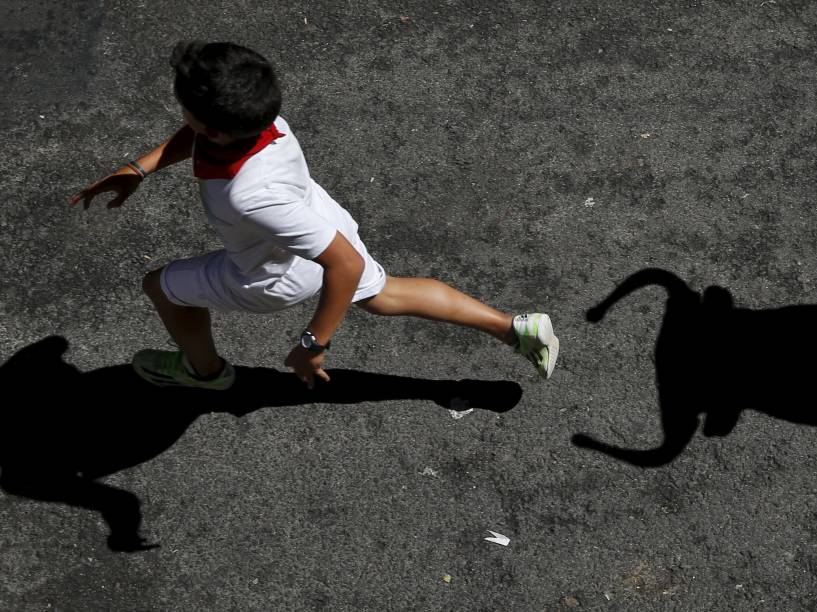 Garoto é perseguido por um touro de brinquedo enquanto participa do "Encierro Txiki", a "pequena corrida de touros", no Festival de São Firmino, em Pamplona, Espanha