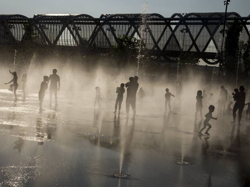 Pessoas brincam enquanto se refrescam em uma fonte pública em Madri, Espanha, onde a temperatura chega a 40 graus Celsius