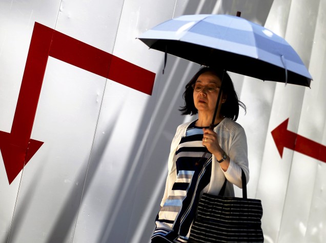 Japonesa é fotografada caminhado com um guarda-chuva pelas ruas do distrito comercial de Tóquio, Japão - 15/07/2015