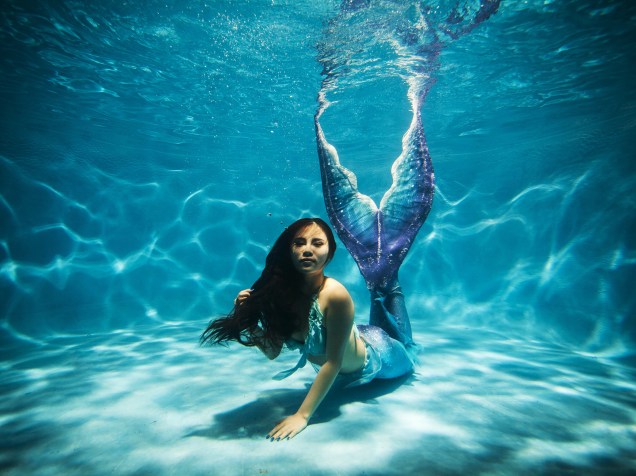 Mulher posa para foto, vestida de sereia, em uma piscina na cidade de Chongqing, na China