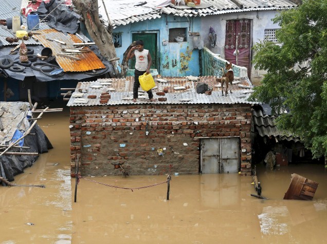Após fortes chuvas na região, garoto e seu cachorro se refugiaram no teto de uma casa nas margens do rio Sabarmati, em Ahmedabad, Índia