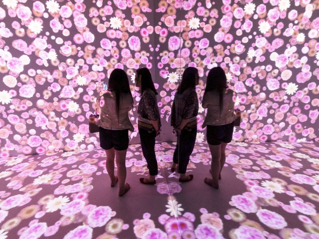 Visitantes observaram projeção de flores na parede e no chão de uma sala em um shopping de Xangai, na China