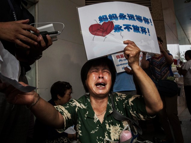 Parente de um passageiro do voo MH370 da Malaysia Airlines, desaparecido há mais de um ano, reage enquanto espera por informações do lado de fora do escritório companhia aérea em Pequim, na China - 06/08/2015