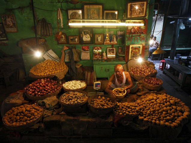 Vendedor pesa batatas em sua barraca num mercado de Calcutá, na Índia - 12/08/2015