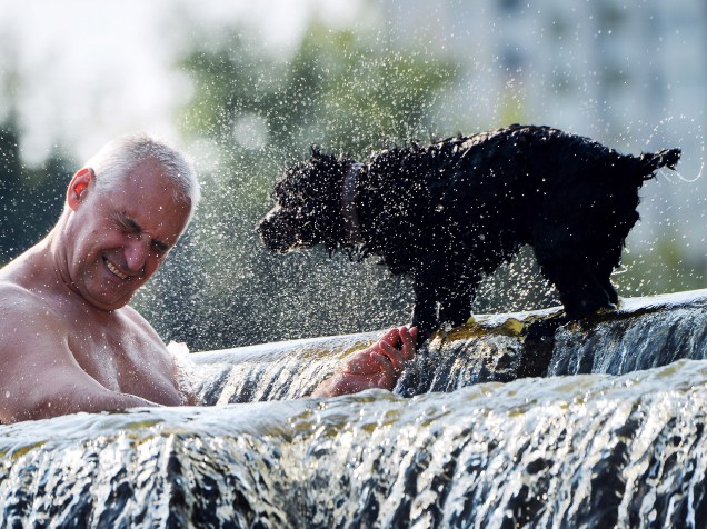Cão se sacode ao lado de um homem que se refresca em uma fonte no centro de Minsk, na Bielorrússia - 12/08/2015