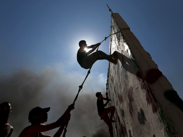 Jovens palestinos escalam uma parede durante exercício num acampamento de verão organizado pelo movimento Jihad Islâmica, em Khan Younis, sul da Faixa de Gaza - 13/08/2015