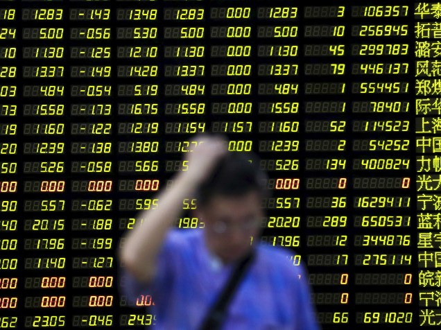 Investidor passa por um painel eletrônico com informações de ações em uma corretora de Xangai, na China. As ações chinesas cairam 8,54% nesta segunda-feira (24)