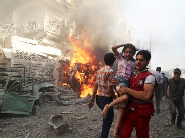 Bombeiro carrega uma criança após uma explosão, o que ativistas disseram ter sido um bombardeio de forças leais ao governo de Bashar al-Assad no bairro de Douma, em Damasco, capital da Síria