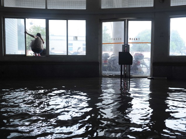 Mulher sobe em janela para evitar a água em uma prédio inundado em Xangai. Chuva forte vinda de uma frente fria e fortalecida pelo tufão Goni trouxe enchentes a muitos distritos de Xangai, China