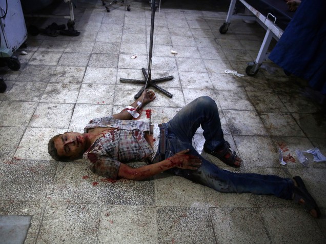 Homem ferido é visto no chão de um hospital improvisado na área dominada por rebeldes de Douma, leste da capital Damasco, após novos ataques liderados por forças aliadas ao governo sírio - 24/08/2015