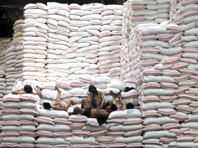 Trabalhadores descansam sobre sacos de arroz empilhados em um armazém da Autoridade Nacional de Alimentos (NFA), na cidade de Taguig, nas Filipinas - 25/08/2015