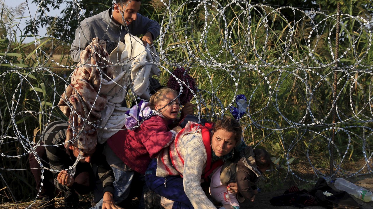 Imigrantes sírios tentar passar por baixo de cerca para entrar na Hungria, na fronteira com a Sérvia. A Hungria iniciou a construção de uma cerca de 175 km na região e planeja reforçar a segurança com helicópteros, polícia montada e cachorros - 27/08/2015