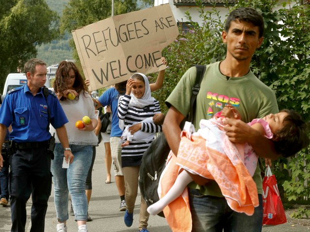 Policial suiço acompanha imigrantes da Síria que carregam seus filhos, após chegada em uma estação de trem no nordeste da cidade de Buchs, Suiça - 01/09/2015