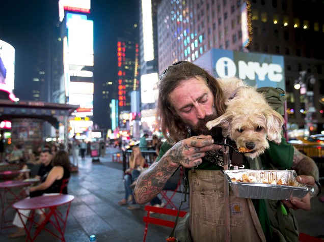 Deke Breuer dá pedaço de lasanha ao seu cão Cahlupa na Times Square, em Nova York. Breuer, que é de Detroit, está viajando pelo país e tem ensinado muitas coisas ao seu companheiro