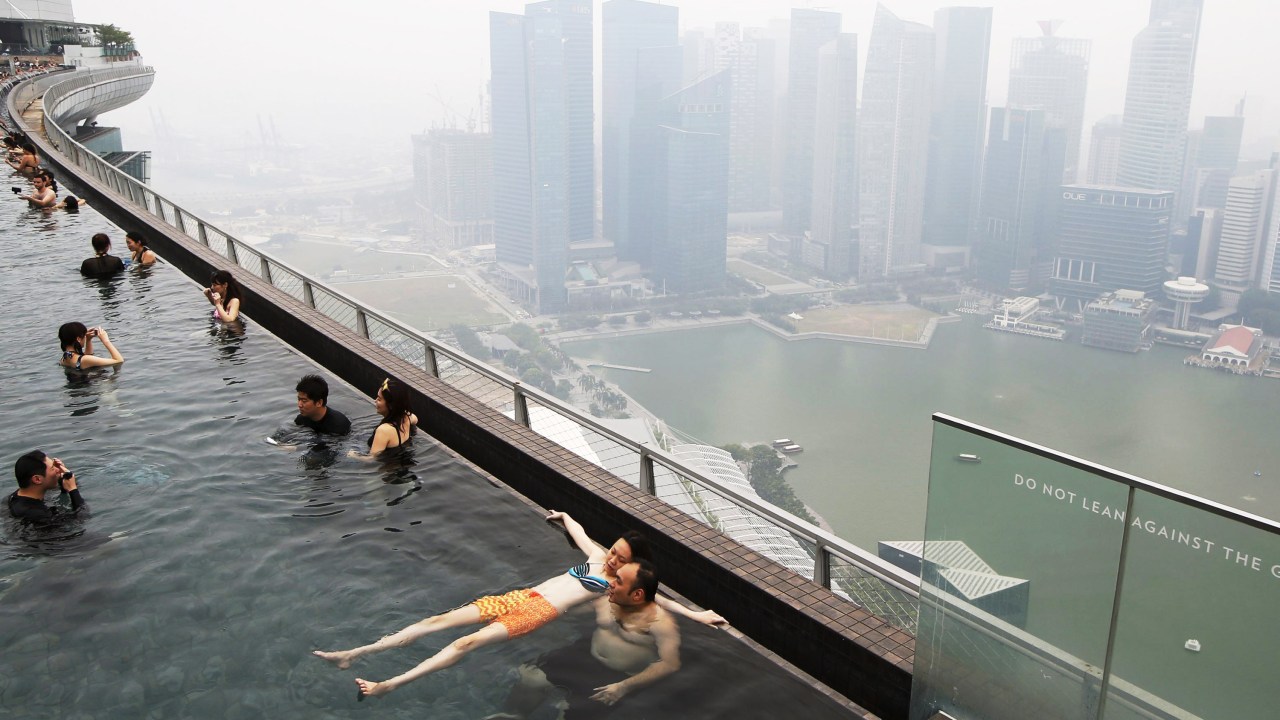 Pessoas nadam em uma piscina com vista para o skyline do distrito comercial em Singapura - 14/09/2015