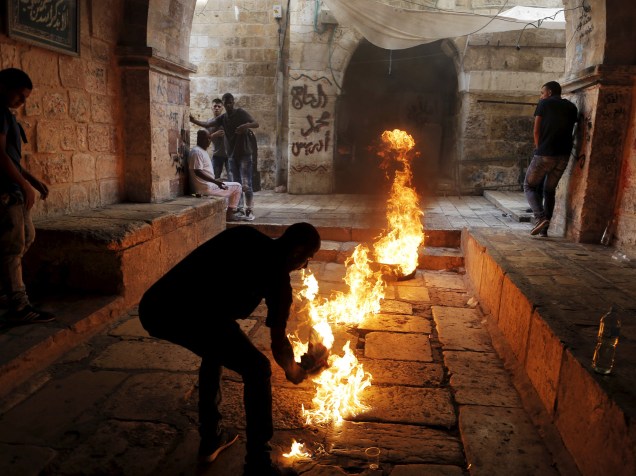 Manifestante palestino chuta um pneu em chamas durante confrontos com policiais israelenses na Cidade Velha de Jerusalém - 15/09/2015