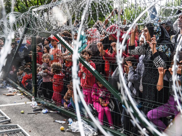 Refugiados ficam atrás de uma cerca de arame farpado na fronteira húngara com a Sérvia, perto da cidade de Horgos - 16/09/2015