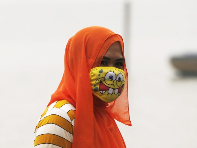 Mulher usa máscara para se proteger de atmosfera contaminada por fumaça de incêndios florestais em Jambi, província da Indonésia - 17/09/2015