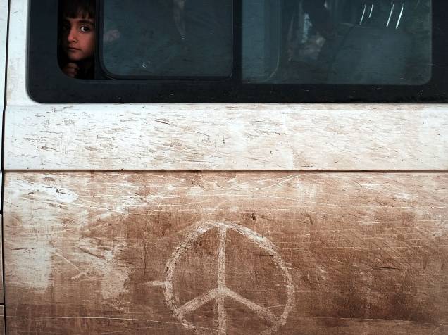 Menino recém chegado da Turquia olha da janela de um ônibus em um centro de acolhimento de refugiados na ilha de Lesbos, em Sikaminias, na Grécia - 19/10/2015