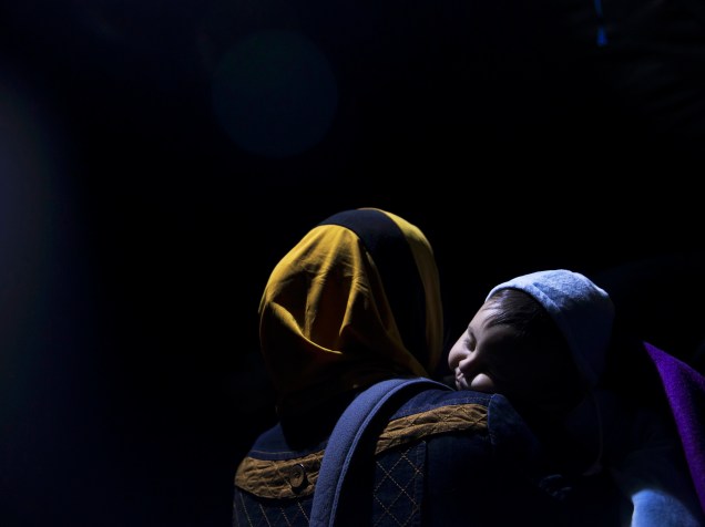 Refugiada carregando uma criança esperava para cruzar a fronteira com a Croácia, perto da aldeia de Berkasovo, na Sérvia