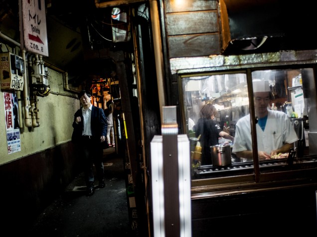 Homem passa em frente a um pequeno restaurante em um beco na cidade de Tóquio, no Japão - 19/10/2015