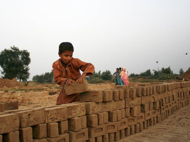 Garoto empilha tijolos em uma fábrica na cidade de Faisalabad, no Paquistão - 19/10/2015