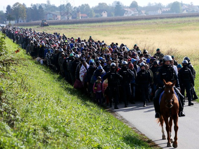 Policiais escoltam imigrantes próximo à fronteira entre a Croácia e a Eslovênia, nesta terça-feira (20)
