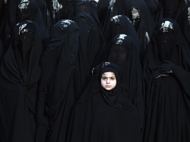 Meninas iraquianas, cobrem o rosto com véus ao participar de um desfile da Ashura, festa religiosa que lembra o martírio de Hussein, o terceiro imã dos xiitas e neto do profeta Maomé, em Bagdá - 23/10/2015