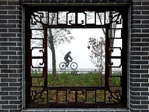 Chinês pedala ao longo das margens de um lago em Hongze, na província de Jiangsu