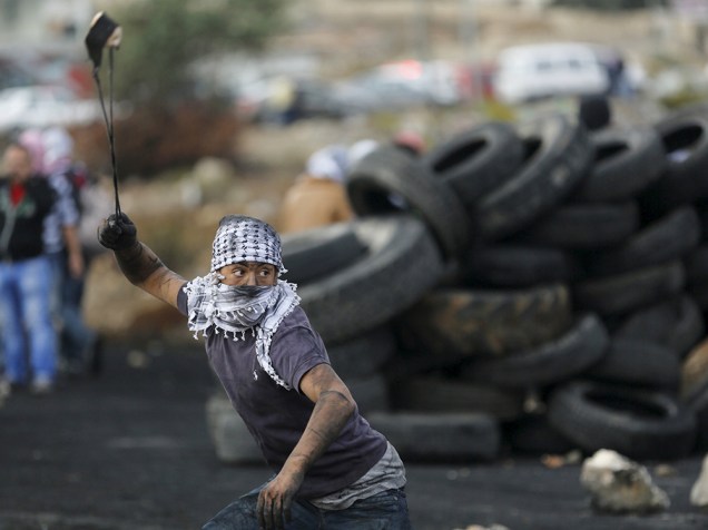 Manifestante palestino joga pedras em tropas israelenses durante confrontro próximo a um assentamento judeu em Ramallah - 27/10/2015