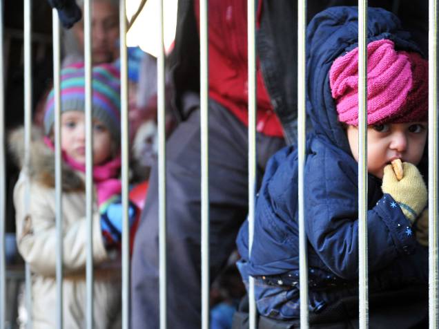 Crianças refugiadas esperam com seus pais, para cruzar a fronteira entre a Sérvia e a Croácia - 28/10/2015