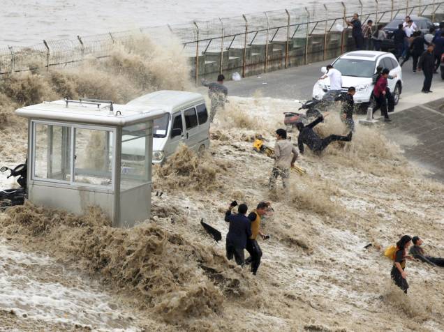 Visitantes são atingidos por uma onda que ultrapassou uma barreira nas margens do rio Qiantang em Hangzhou, China - 28/10/2015