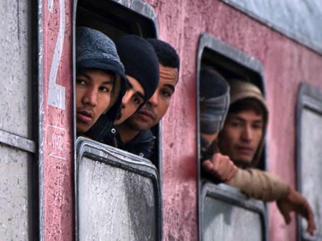 Imigrantes e refugiados olham pela janela de um trem partindo para a Sérvia. Mais de 700,000 refugiados chegaram às costas mediterrânicas da Europa ao longo deste ano, em meio à pior crise migratória desde a Segunda Guerra Mundial