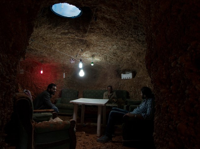 Abu Amer, um ex-perfurador de poços, senta-se com os membros da família dentro de um abrigo subterrâneo, construído por ele, no subúrbio de Aleppo, na Síria - 29/10/2015