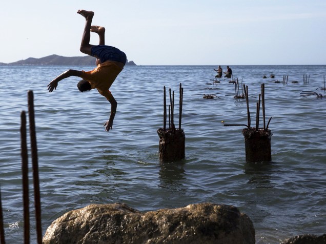 Garoto salta no mar das ruínas de uma doca, na baía de Rio Caribe, na Venezuela - 30/10/2015