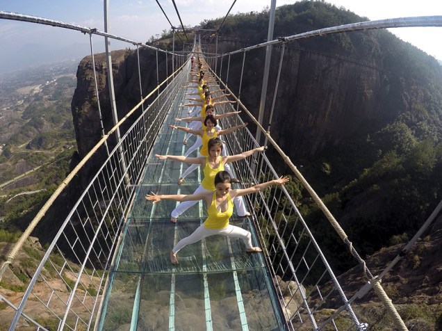 Mulheres praticam ioga em uma ponte de vidro no National Geo-parque Shiniuzhai, na China