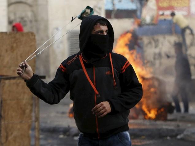 Palestino lança pedra contra forças de segurança israelenses durante confrontos no centro da cidade de Hebron, na Cisjordânia, nesta quinta-feira (05)